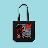 Black tote bag with abstract design by KC Hall on a light blue background